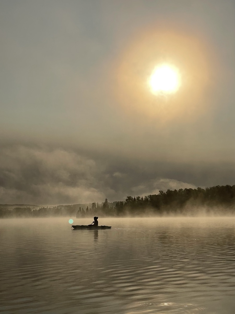 Kayaking at sunrise on a misty lake